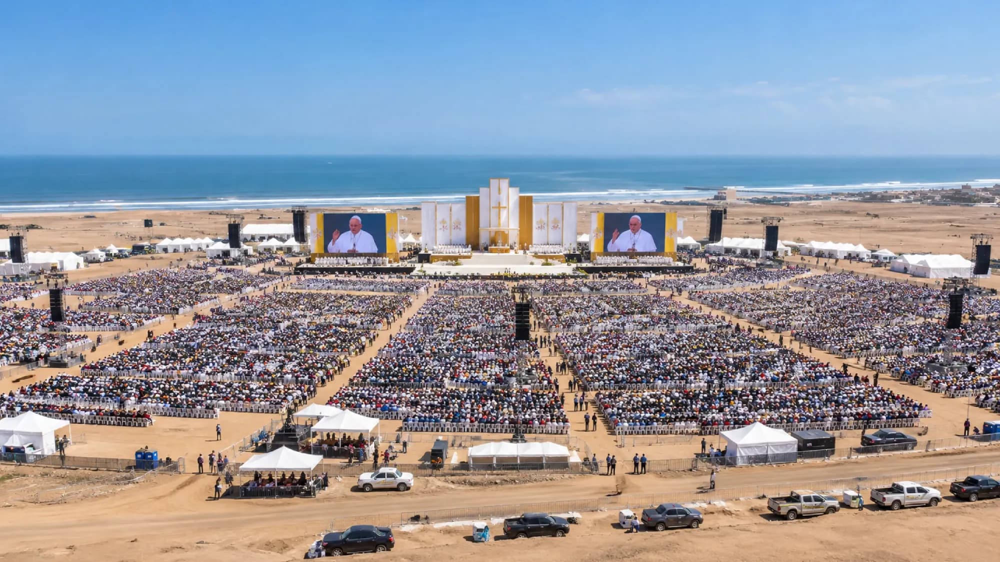 Vista aérea de una explanada frente al mar con miles de asistentes durante una misa papal