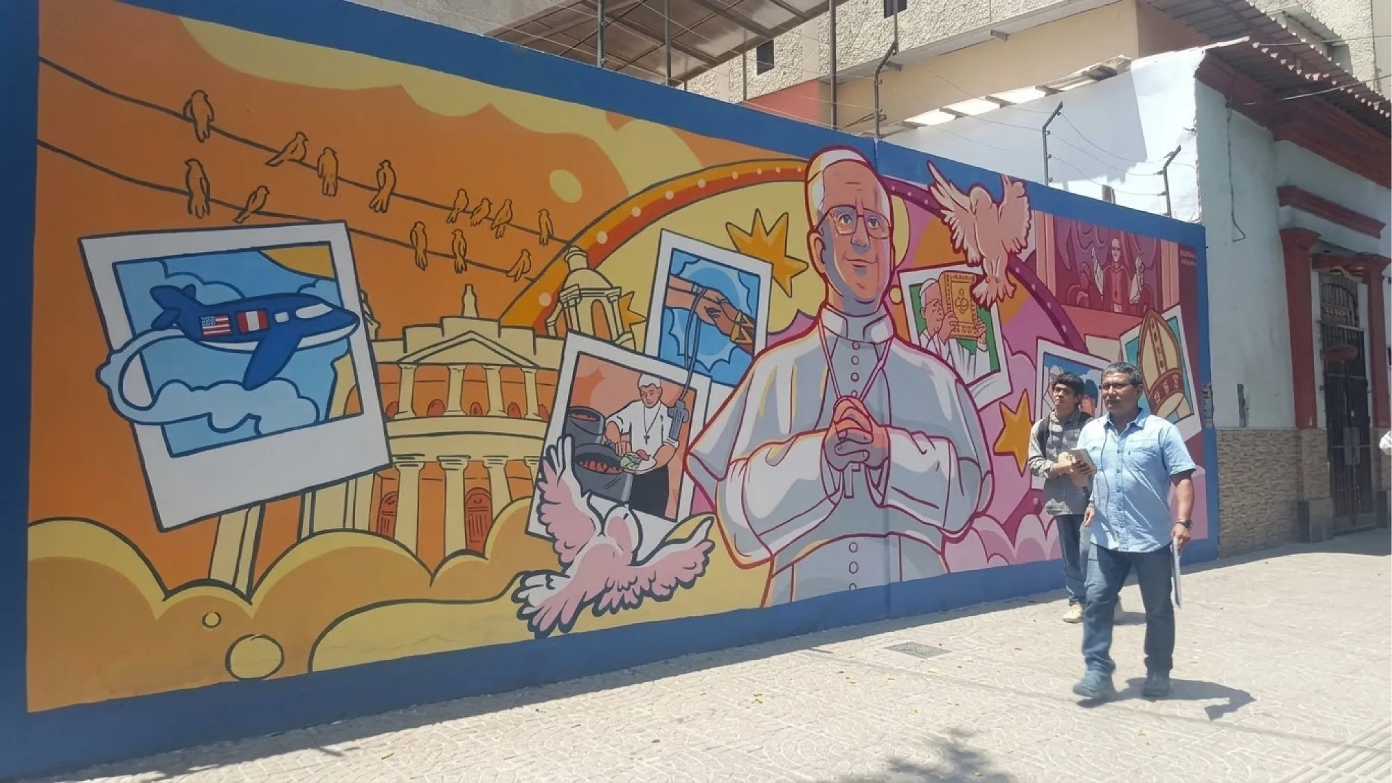 Mural colorido con la figura del Papa León XIV y escenas de su vida, frente al que caminan dos personas
