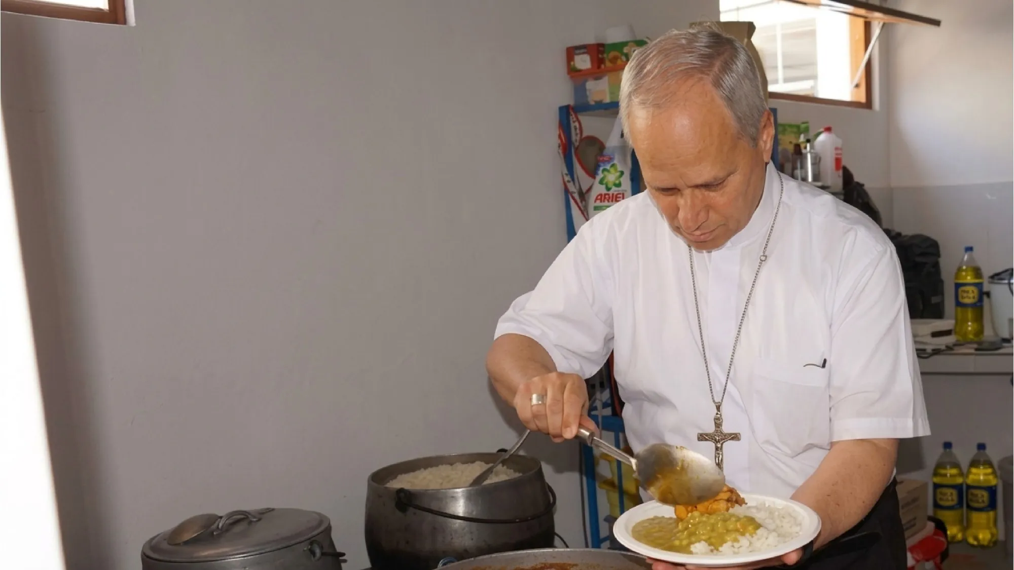Robert Prevost sirviendo un plato de comida en una cocina comunitaria
